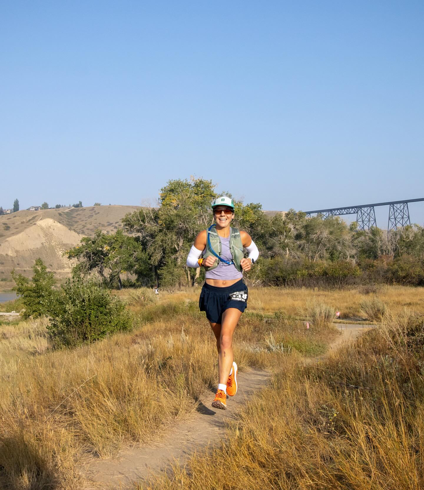 Cassandra de Winter trail running in Alberta with the Lethbridge High Level Bridge in the background